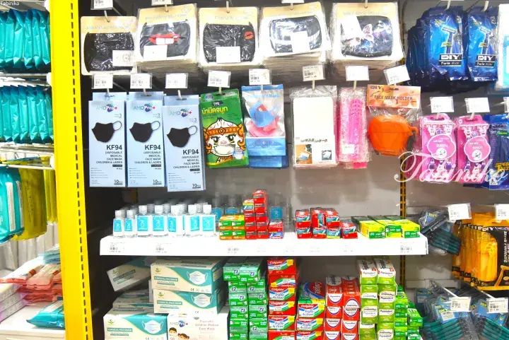 Shelves stocked with face masks, hand sanitizers, and Colgate toothpaste at a Malaysian retail store.