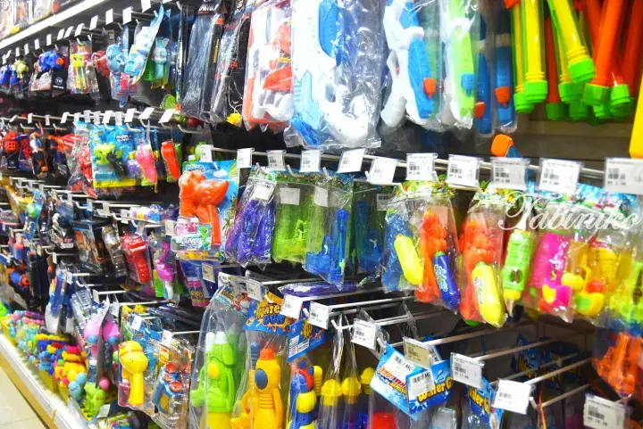 Colorful water guns and bubble toys hanging on shelves in a Malaysian store.