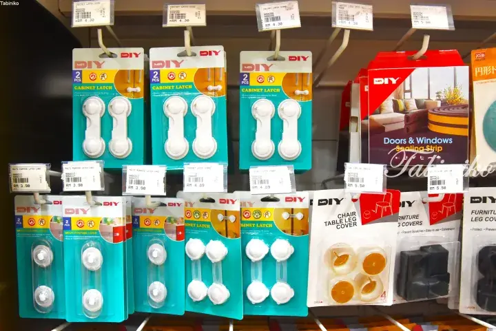 MR DIY store shelves displaying various child safety cabinet latches and furniture leg covers with price tags.