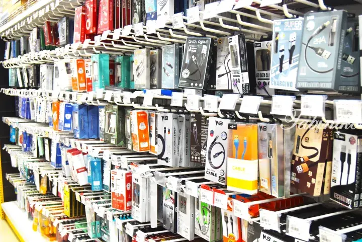Shelves stocked with various mobile phone chargers and data cables in a retail store.