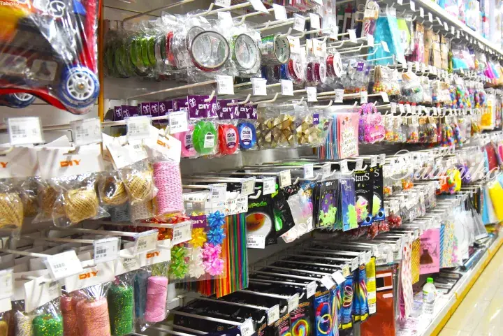 Colorful craft supplies including ribbons, twine, and decorations neatly arranged on store shelves.