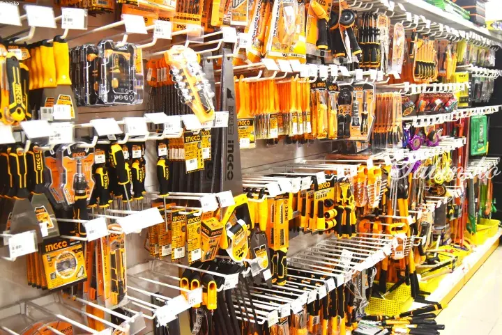 Shelves stocked with various orange and black Incco brand tools including screwdrivers, saws, and paint brushes.