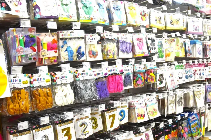Shelves stocked with colorful latex and foil balloons in various shapes and sizes at a Malaysian party supply store.