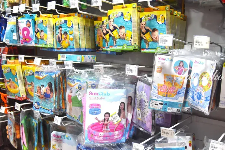 Shelves stocked with colorful children’s swimming gear like armbands and inflatable pools at a Malaysian retail store.
