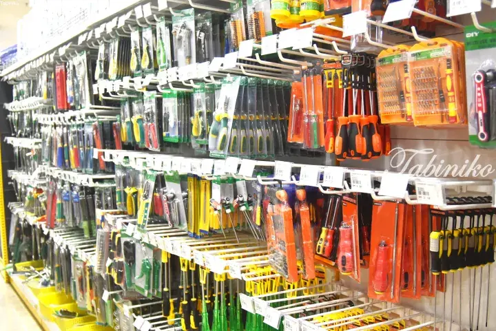 Aisle filled with various packaged hand tools like screwdrivers and pliers in a hardware store.