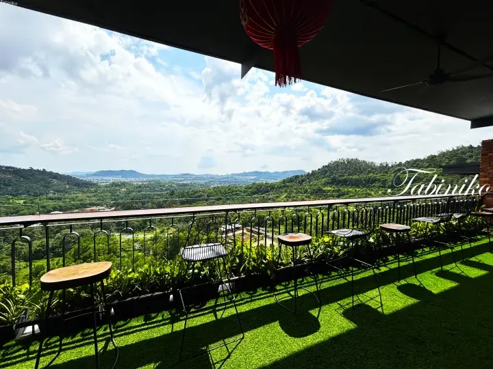 Balcony with high stools overlooking lush green hills and a scenic valley view.