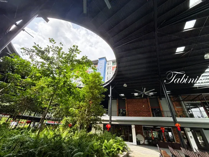 Modern commercial building with circular skylight, lush greenery, and red lanterns at Tabini Mall.