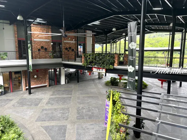 Interior view of Haberdashery in Muzium Village, showcasing its open-air design, brick architecture, and lush greenery.