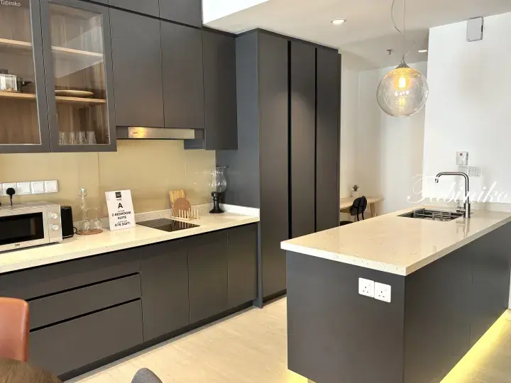 Modern kitchen with dark grey cabinets, white countertops, and an island featuring a sink and pendant light.