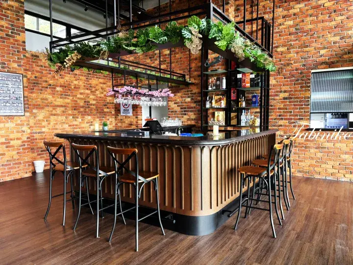 Modern bar with wooden counter, brick walls, and hanging greenery in a stylish interior.