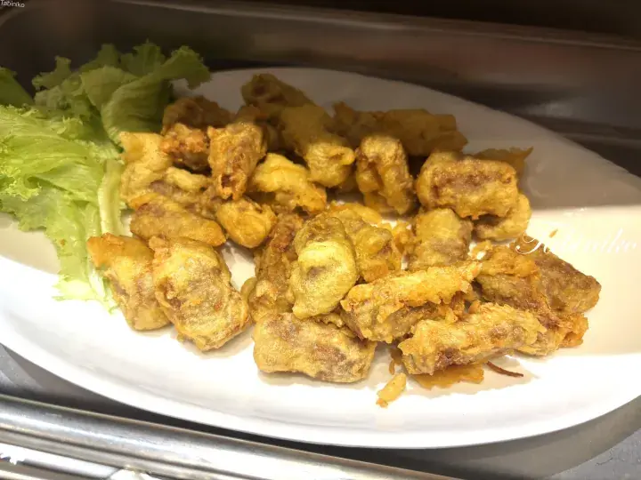 Golden fried chicken pieces served on a white plate with fresh lettuce garnish.
