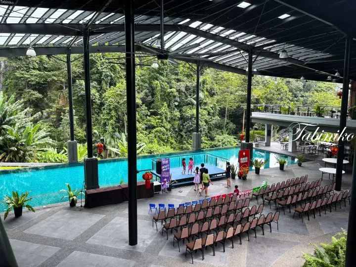 Outdoor poolside event area with stage, seating, and lush greenery at Tabiniko resort.