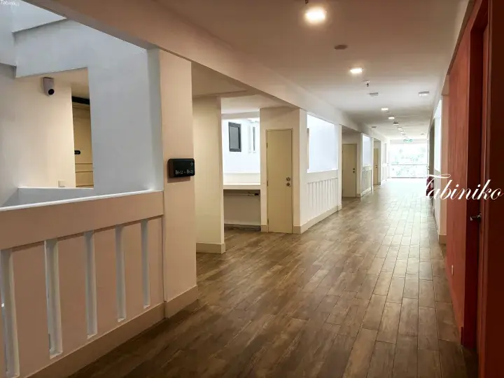 Bright hallway with wooden flooring and cream walls in a modern Malaysia property, featuring a security panel and clean design.