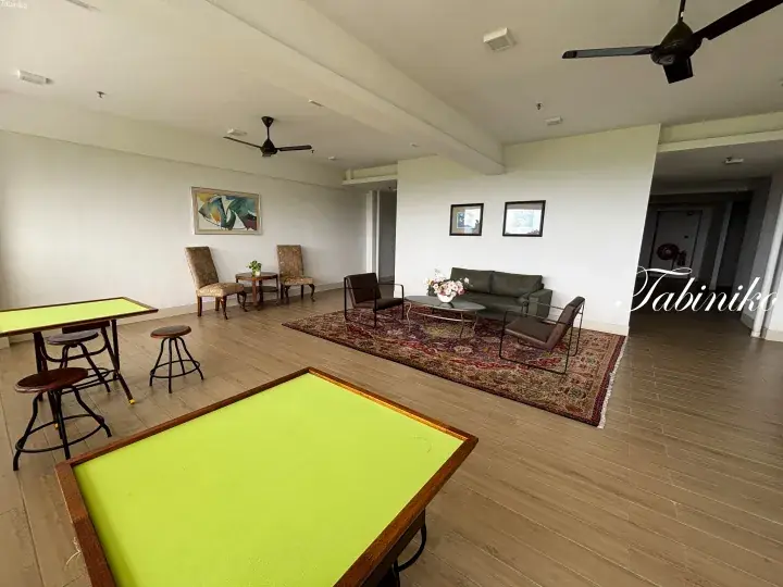 Spacious open-plan living area with wooden floors, a green game table, and a cozy lounge setup.
