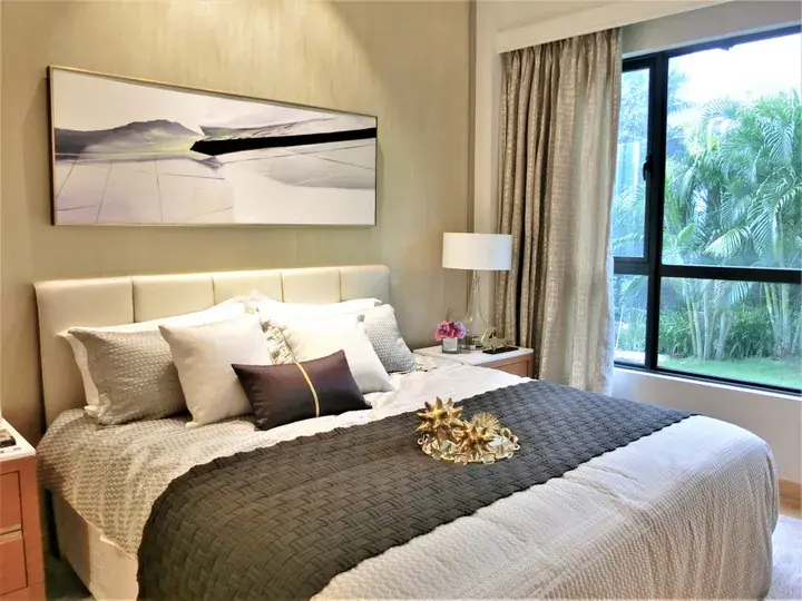 Modern bedroom with a king bed, abstract wall art, and a large window overlooking lush tropical greenery.