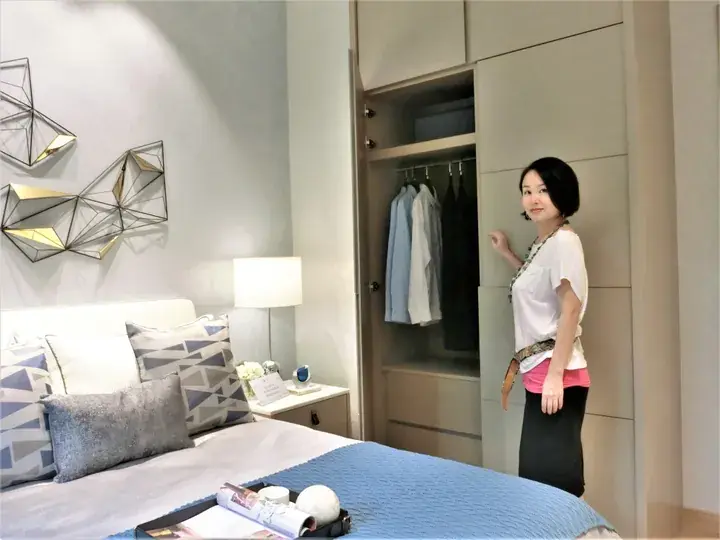 Woman standing beside a modern built-in wardrobe in a stylish bedroom with geometric wall art.