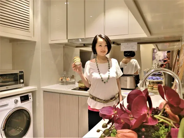 Woman holding a cupcake in a modern kitchen with a washing machine and microwave, showcasing a property lifestyle.