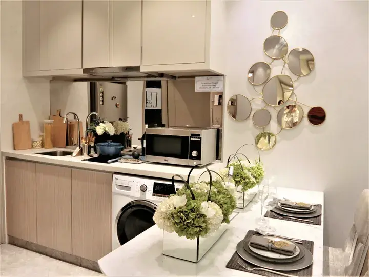 Modern kitchen with a washing machine, microwave, and dining table set with floral arrangements.