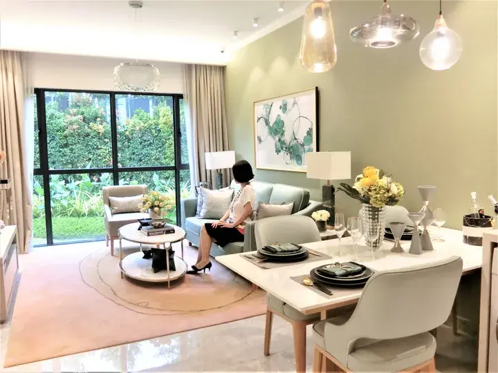 Modern dining and living room with green walls, white furniture, and a view of a lush garden through large glass doors.