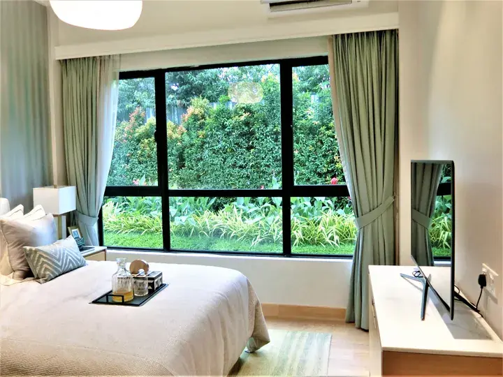 Bright bedroom with a large window overlooking lush greenery, featuring a neatly made bed and modern decor.
