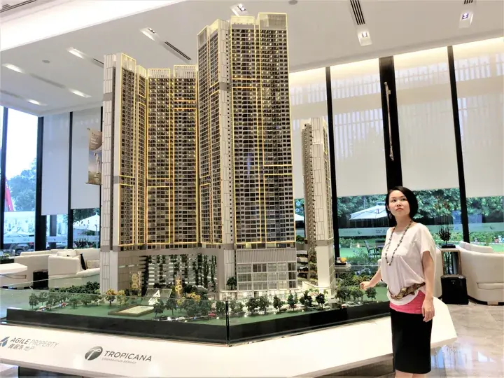 Woman standing beside a large architectural model of the Tropicana Residences high-rise condominium complex.