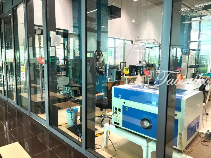 Modern laboratory interior with glass walls, scientific equipment, and a blue machine.