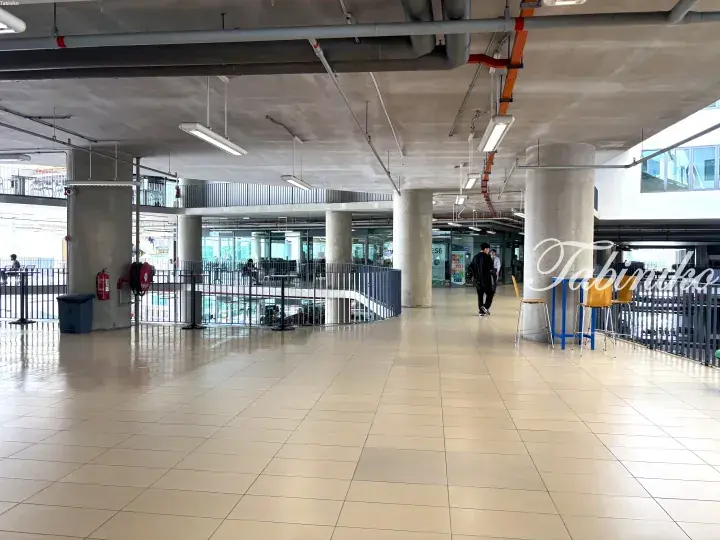 Modern interior corridor with concrete pillars and tiled flooring at a Malaysian transit station.