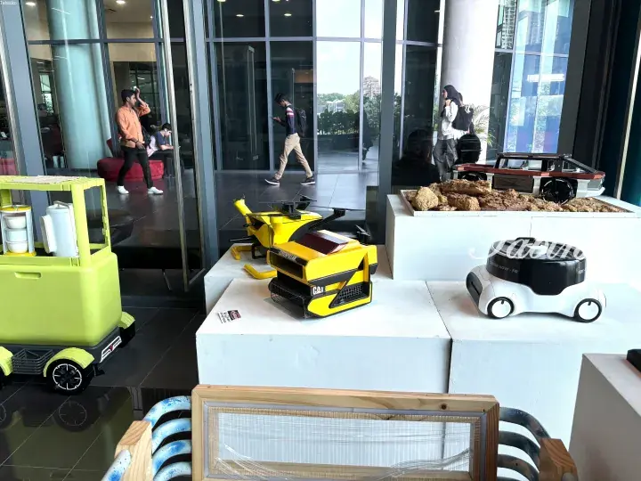 Exhibition of autonomous delivery robots and smart mobility vehicles displayed on white pedestals in a modern building lobby.