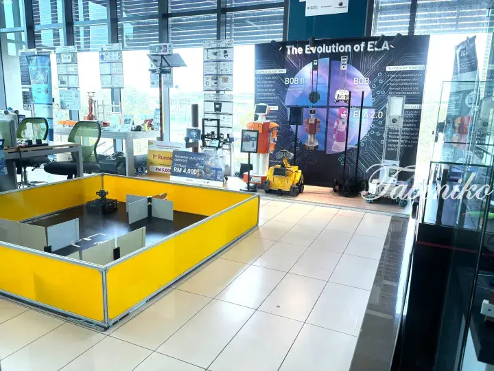 Educational robotics exhibit featuring a yellow obstacle course and displays on robot evolution.