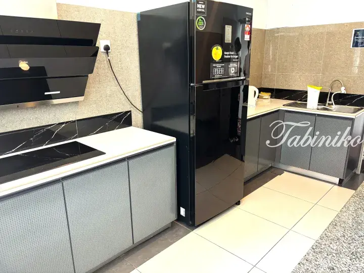 Modern kitchen with black refrigerator, induction cooktop, and grey cabinets in a property listing.