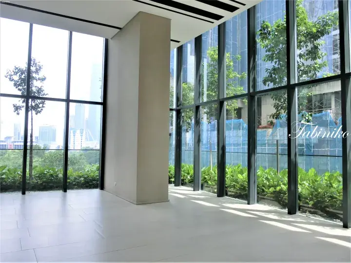 Bright modern interior with floor-to-ceiling windows overlooking lush greenery and city skyline in Malaysia.