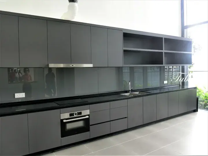 Modern grey kitchen with sleek cabinets, black countertops, built-in oven, and large window in a Malaysian property.