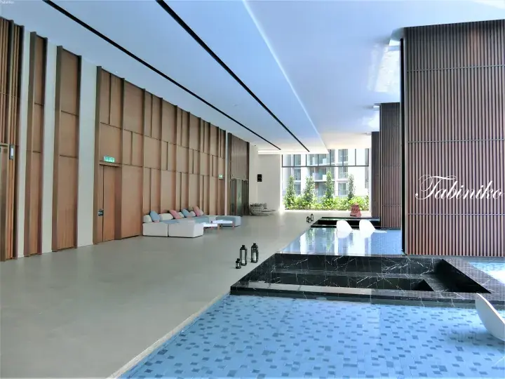 Modern indoor pool area with blue mosaic tiles, wooden panel walls, and a ‘Tabiniko’ logo.