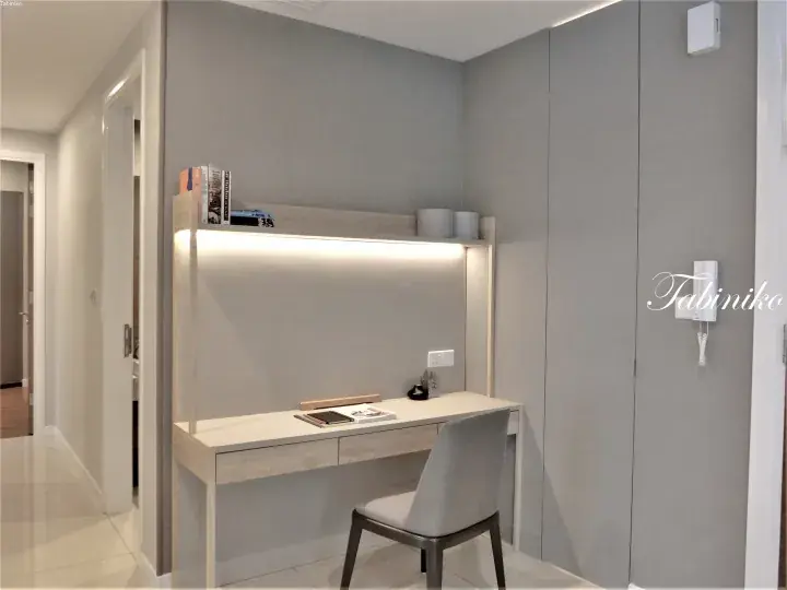 Modern built-in study desk with integrated lighting and shelving in a contemporary apartment.