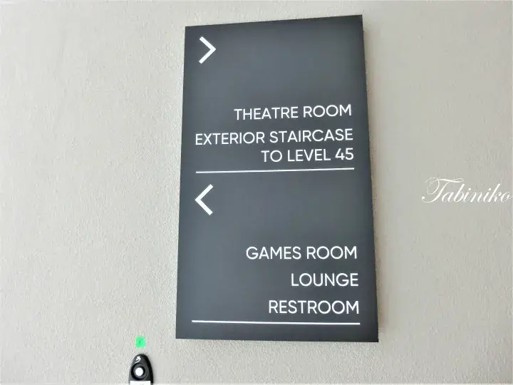 Dark grey directional sign pointing to a theatre room, exterior staircase to level 45, games room, lounge, and restroom.