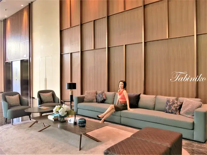 Woman relaxing on a modern sofa in a luxury hotel lobby with wood-paneled walls and elegant decor.