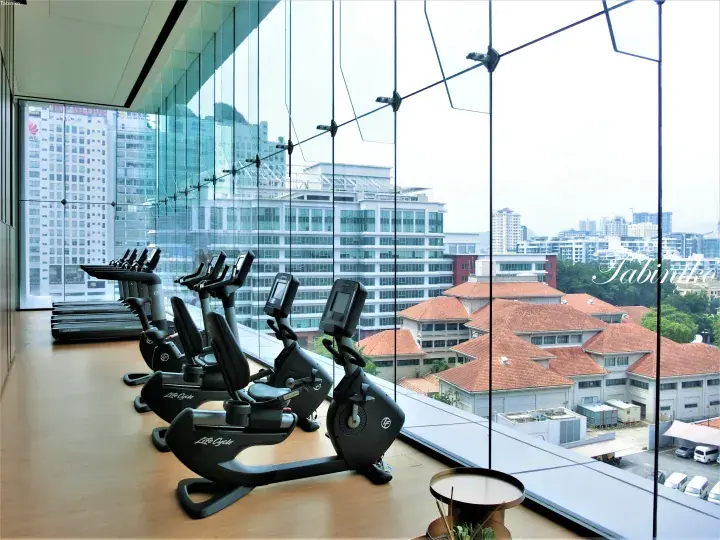 Modern gym with Life Fitness bikes and treadmills overlooking city buildings through floor-to-ceiling windows.