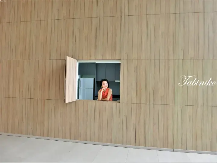 Woman looking out from a small window in a modern wooden wall at a contemporary property.
