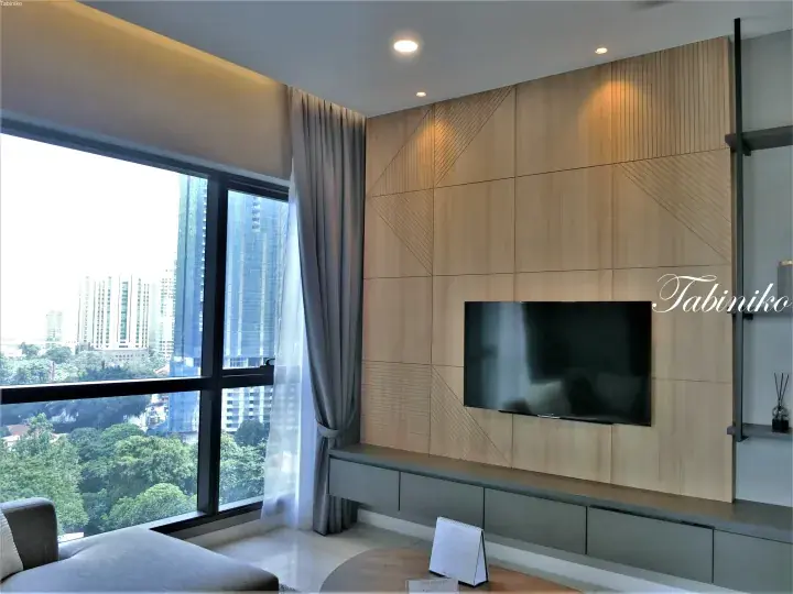 Modern living room with a wooden feature wall, TV, and large window overlooking Kuala Lumpur cityscape.