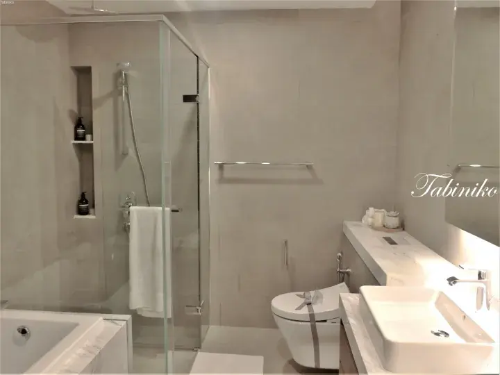 Modern bathroom with glass shower, bathtub, and marble vanity in a luxury property.
