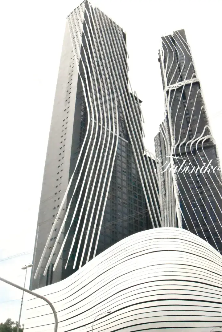 Low-angle view of the distinctive wavy white facade of the Vortex Residences in Kuala Lumpur, Malaysia.