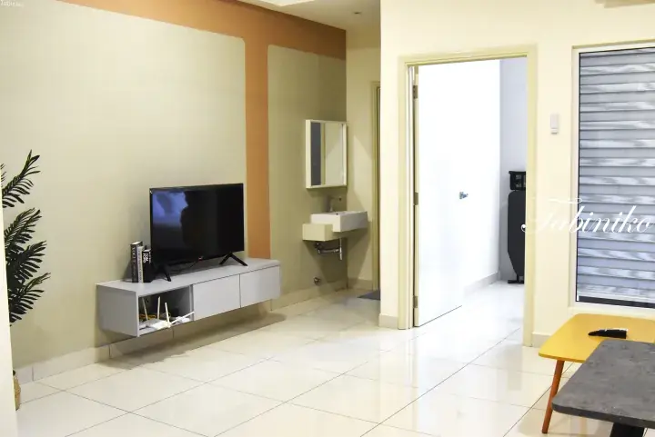 Modern living room with wall-mounted TV, floating cabinet, and open doorway to a bathroom in a Malaysian property.