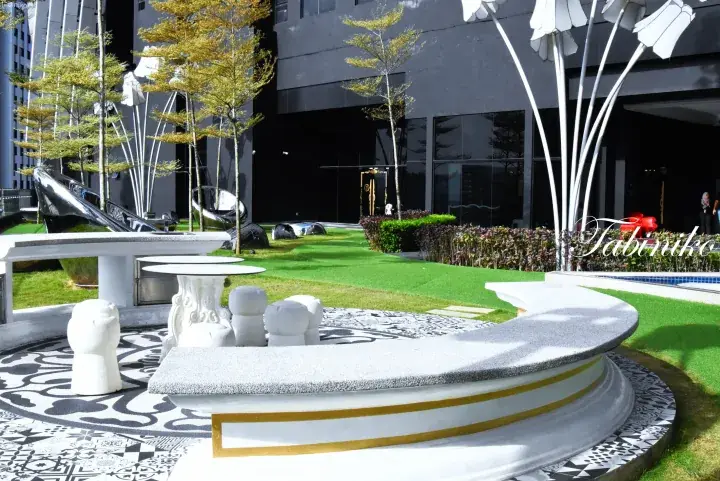 Modern landscaped garden with white floral sculptures and patterned tiles at a luxury property in Malaysia.