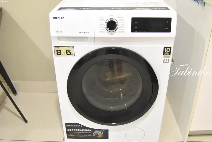 White Toshiba front-loading washing machine with digital display and control panel in a showroom.