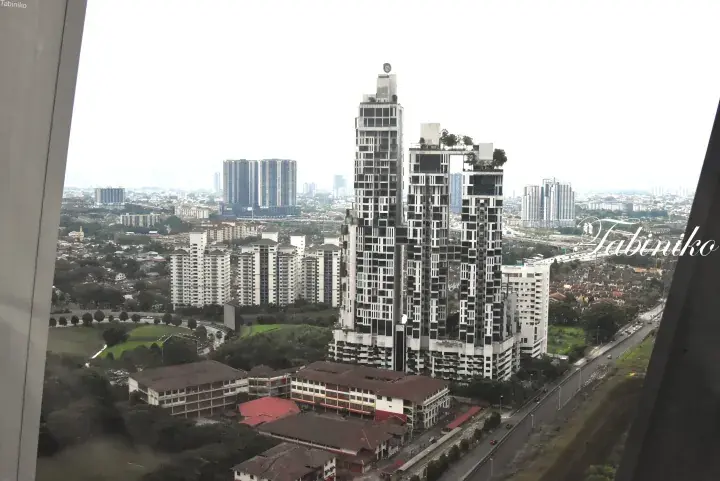 View of distinctive black and white high-rise condominiums in a Malaysian cityscape with surrounding residential areas.