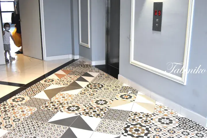 Decorative patterned tiles in a hallway leading to an elevator in a modern property.