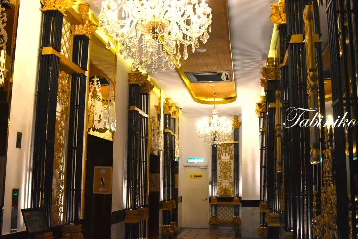 Luxurious hotel lobby with ornate black and gold pillars and elegant crystal chandeliers.