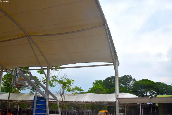 Covered basketball court with white canopy and blue stairs at a school or community facility in Malaysia.