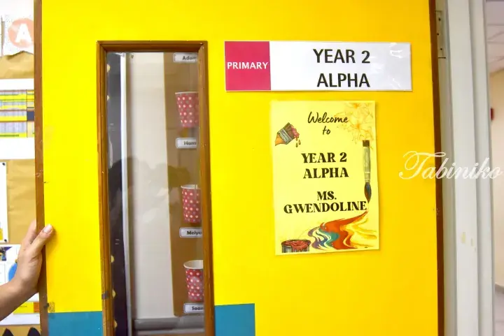 Bright yellow classroom door with a Year 2 Alpha sign and a welcome poster for Ms. Gwendoline.