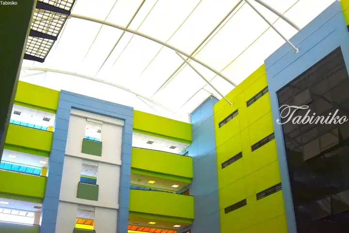 Colorful modern building interior with bright green and blue walls under a large skylight.